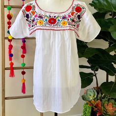 "This traditional Mexican blouse is beautifully made in Merida Yucatan, Mexico, each piece is individually hand made and hand embroidered.  You will love this lightweight blouse made of organic cotton, this natural material gives the blouse a delicate and relaxed feel.   Details: Size M-L measurements: Bust: 42\" - 29\" length(shoulder to bottom Hem) Cotton  thread Embroidered Material: 100% Cotton All items are shipped from the US All Mi Mundo Mexicano  items are 100% handmade by artisans in Mexico. Each stitch and item is completely unique and one-of-a-kind, so you'll never find two that are exactly the same! All  items may vary slightly in size, color, and design - that's what makes handmade items so special and charming!  Your Purchase supports artisans craft and families" Traditional White Embroidered Top, Folk Embroidered Beach Blouse, Folk Style Embroidered Beach Blouse, Embroidered Folk Blouse For Beach, Folk Peasant Top With Multicolor Embroidered Neckline, Peasant Floral Embroidered Top For Beach, Festival Chikankari Embroidered Top, Folk Style Floral Embroidered Top For Festive Occasions, Folk Style Peasant Top With Floral Embroidery For Beach