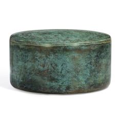 a round metal container sitting on top of a white surface with green pattered paint