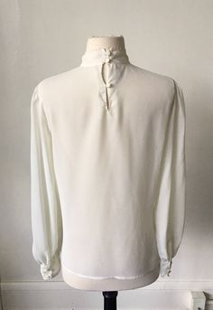 Vintage Floral Embroidered Mock Turtleneck Semi Sheer 1980's 80's Long Sleeve Victorian Edwardian White Blouse. In great condition! Listed as a size 6 but fits like a modern S/M. Measurements are taken while garment is laid flat and are as follows: Shoulders: 15 inches Chest: 19 inches Length: 24.5 inches Sleeves: 24 inches Vintage Bishop Sleeve Formal Blouse, Vintage Bishop Sleeve Blouse For Formal Occasions, Vintage Bishop Sleeve Tops For Fall, Vintage Bishop Sleeve Tops, Vintage White Bishop Sleeve Tops, Vintage Tie Neck Tops For Formal Occasions, Vintage Solid Color Blouse For Daywear, Vintage Tie Neck Blouse For Fall, Vintage Bishop Sleeve Blouse For Daywear