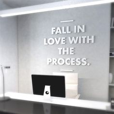 a desk with a computer on it and a sign that says fall in love with the process