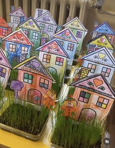 there are many houses in the grass on this table and one is painted with children's drawings