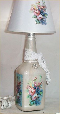 a lamp with flowers painted on it and a lace around the base is sitting on a table