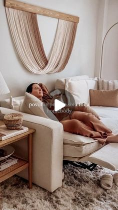 a woman laying on top of a couch in a living room