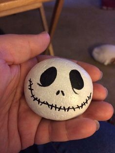 a hand holding a rock with a jack skelling face painted on it's side