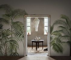 an open door leading to a dining room with palm trees in the corner and a round table