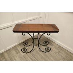 a wooden table sitting on top of a hard wood floor next to a white wall