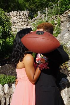 a man and woman kissing with a football on their head