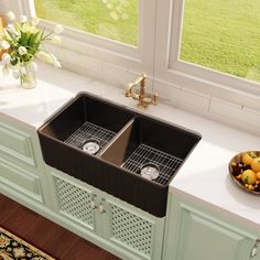 a kitchen sink sitting under a window next to a bowl of fruit