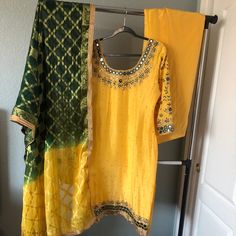 It’s A Yellow Top With Mirror/ Stone Embroidery Top With Full Work On Sleeves. Comes With Matching Yellow Salwar, And Ombr Emerald Green/ Yellow Chunni. Brand New. Estimated Measurements: Suit- Bust 40, Waist 42, Length 42 Salwar Length: 43. Margins 2 1/2’ Each Side Outfits Will Not Fit Into A Standard Size Category, All Of The Outfits Are Custom Made. *Most Outfits Are Pre Worn Unless Stated. Worn Items Will Show A Few Signs Of Wear Including Minor Stains, Missing Stones Around The Heavy Pieces Elegant Yellow Kurta With Mirror Work, Mustard Salwar Kameez For Festivals, Unstitched Yellow Sets For Summer, Yellow Salwar Kameez With Mirror Work For Festivals, Yellow Salwar Kameez With Gold Embroidery For Eid, Yellow Salwar Kameez With Gold Embroidery For Festive Occasions, Traditional Yellow Kurta With Gold Embroidery, Festive Yellow Salwar Kameez With Mirror Work, Festive Yellow Salwar Kameez With Gold Embroidery