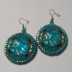 Hand-made beaded earrings: Colors: Teal w/fire colors  Closure: Hook size: 2 inches Beaded Round Earrings For Festival, Turquoise Beaded Round Earrings, Unique Colorful Beaded Round Earrings, Unique Turquoise Beaded Earrings, Festive Turquoise Beaded Earrings, Artisan Bead Cap Earrings, Handmade Turquoise Beaded Earrings With Czech Glass, Turquoise Beaded Earrings With Czech Glass, Turquoise Beaded Earrings In Czech Glass