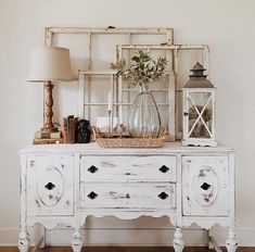 an old white dresser with flowers in a vase on top and other items around it