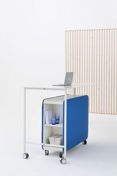 a laptop computer sitting on top of a blue and white cart next to a wooden wall