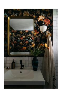 a bathroom sink sitting under a mirror next to a wall mounted faucet with flowers on it