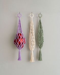 three pieces of string art hanging from hooks on a white wall next to each other