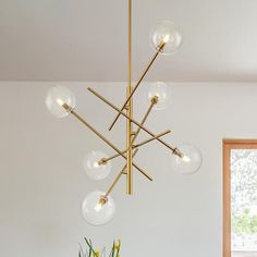 a modern chandelier hanging from the ceiling in a dining room with white walls