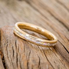 a gold wedding band on top of a wooden table