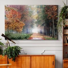 a painting hanging on the wall above a dresser in a room with bookshelves