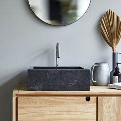 a bathroom sink sitting on top of a wooden cabinet next to a mirror and vase