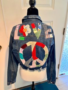 a jean jacket with colorful patches on it sitting on top of a mannequin