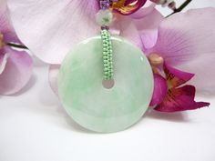 "This beautiful purple woven string coupled with the Jade bead's necklace which comes with a handcrafted Grade AAA natural light green Jade Donut (平安扣) as an auspicious symbol of peace and safety and will protect the wearer against evil. The Grade AAA natural light green Jade Donut (平安扣) measures approximately 2\" dia. x 1/4\" thickness (4.9cm dia. x 0.6cm). The total weight of the necklace is 33g. The necklace comes with an adjustable woven string with its shortest at approximately 20\" and can Spiritual Jade Beaded Necklace, Spiritual Round Jade Beaded Necklace, Handmade Jade Necklaces For Good Luck, Spiritual Round Jade Beaded Necklaces, Handmade Round Necklace For Blessing, Handmade Round Necklaces For Blessing, Handmade Symbolic Green Necklace, Green Hand-wrapped Beaded Necklaces As Gift, Green Beaded Necklace With Large Pendant For Gift