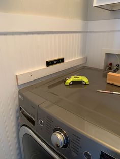 a washer and dryer in a small room with white paneling on the walls