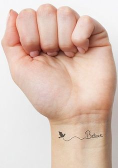 a woman's wrist tattoo with the words believe and a small bird on it