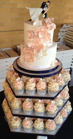 a three tiered wedding cake with cupcakes on it