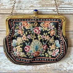 an old purse hanging from a chain on a wooden wall with flowers in the middle