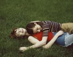 two young women laying on the grass in front of each other with their eyes closed