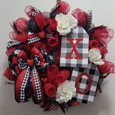 a wreath that has the letter x on it and is decorated with red, white and black ribbon