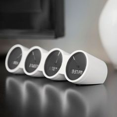 three white speakers sitting on top of a table next to a black and white vase