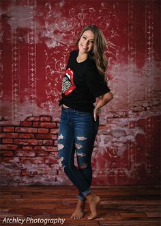 a woman standing in front of a red brick wall with her hands on her hips