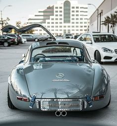 a silver sports car parked in a parking lot next to other cars and palm trees