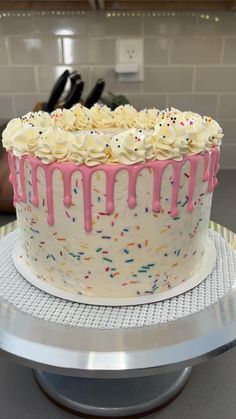 a cake with white frosting and sprinkles sitting on top of a counter