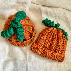 two crocheted pumpkins sitting on top of a white bed sheet next to each other