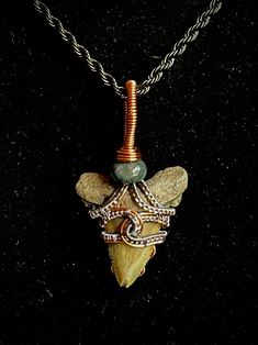 "2\" unrestored Megalodon Shark tooth (2-23 million years old) is wrapped in pewter colored copper wire and copper wire; a green quartz bead crowns the pendant.    Many cultures believe shark teeth are sacred objects, bringing strength, healing, clarity, and positive energy. They are connected to the root chakra, promoting grounding and survival. Thank you for shopping with Ancientish!" Rustic Hand Wrapped Copper Jewelry, Collectible Artisan Copper Jewelry, Unique Wire Wrapped Necklaces For Collectors, Artisan Copper Jewelry For Collectors, Unique Wire Wrapped Necklace, Unique Arrowhead Natural Stone Jewelry, Unique Arrowhead Jewelry With Natural Stones, Antique Electroformed Pendant Jewelry, Rustic Wire Wrapped Copper Jewelry