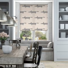 a dining room table with chairs and a window covered in roman blind blinds that have birds on them