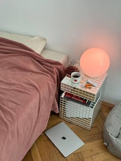 a bedroom with a bed, nightstand and laptop on the floor