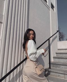 a woman is walking down the stairs with her hand on her hip and wearing a white sweater