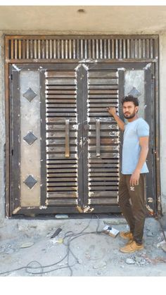 a man standing in front of a door with metal bars on the side and one hand up