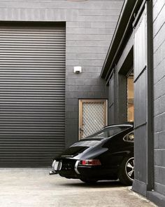 a black sports car parked in front of a garage door