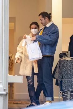 a man and woman wearing face masks while holding shopping bags