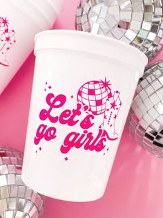 a white cup with the words let's be girls printed on it next to disco balls