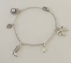 This Coastal Cowgirl Silver Charm Bracelet is the perfect accessory for every outfit. This dainty bracelet boasts an eclectic mix of charms, including a cowgirl boot charm for the coastal cowgirl, a delicate heart charm, a chic bow charm, a radiant star charm, and a seashell charm that ties all the pieces together. Get this charm bracelet for everyday wear or for the perfect gift! Charm Jewelry Silver, Silver Charm Bracelet Aesthetic, Silver Charm Bracelets, Bracelets Hippie, Charm Bracelet Silver, Bracelet With Charms, Cowgirl Boot, Hippie Bracelets, Diy Charm Bracelet