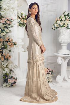 An elegantly embroidered shirt featuring gorgeous dabka work floral embroidery in gold & silver with sequins, pearls, resham, tila and gota work on stunning Maysuri net base. This classic ivory gold shirt is paired with stylish pleated dhaka pants. A fully embellished pure Indian Silk tissue dupatta, trimmed with lace, gota & kiran dhanak adding an elegant flair to final look. Pair this outfit with our hand-made potli bag, a must have outfit for Nikkah, engagement and other celebratory occasions Designer Gold Tissue Silk Palazzo Set, Gold Tissue Silk Palazzo Set For Eid, Gold Tissue Silk Palazzo Set With Resham Embroidery, Elegant Traditional Wear With Pearl Embroidery For Reception, Gold Palazzo Set With Dabka Work In Tissue Silk, Eid Cream Palazzo Set With Mirror Work, Cream Palazzo Set With Mirror Work For Eid, Elegant Beige Palazzo Set For Diwali, Festive Embellished Beige Sets