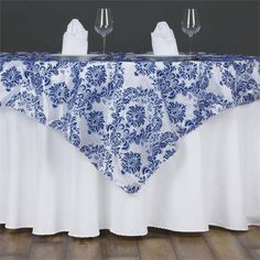 two wine glasses sitting on top of a table covered in a blue and white damask