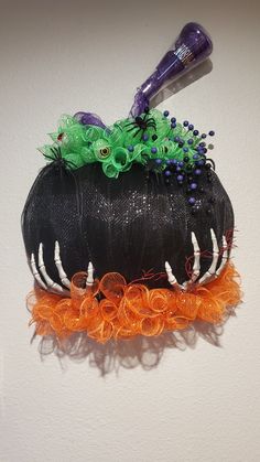 a hair dryer sitting on top of a black hat with orange and green decorations