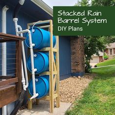 a rack with three blue barrels attached to it in front of a house that has the words stacked rain barrel system diy plans