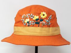 This hand embroidered cotton bucket hat is a stylish accessory that combines function with unique, handmade design. Made from high-quality cotton, it provides comfort and protection from the sun, making it perfect for outdoor activities. The intricate floral embroidery is meticulously crafted by hand, giving each hat a one-of-a-kind touch. Whether you're at the beach, camping, or just running errands, this cotton hat is both practical and fashionable. Item: flower embroidered bucket hat Material Orange Cotton Beach Hat, Orange Cotton Bucket Hat For Summer, Orange Cotton Summer Hat, Summer Orange Cotton Bucket Hat, Adjustable Orange Cotton Bucket Hat, Orange Cotton Bucket Hat, Adjustable Orange Bucket Hat For Spring, Yellow Cotton Bucket Hat With Short Brim, Custom Embroidered Cotton Summer Hats