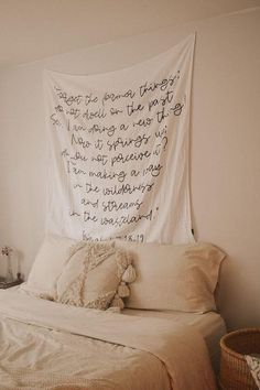 a bed with a white blanket hanging over it's headboard and pillows on top of it